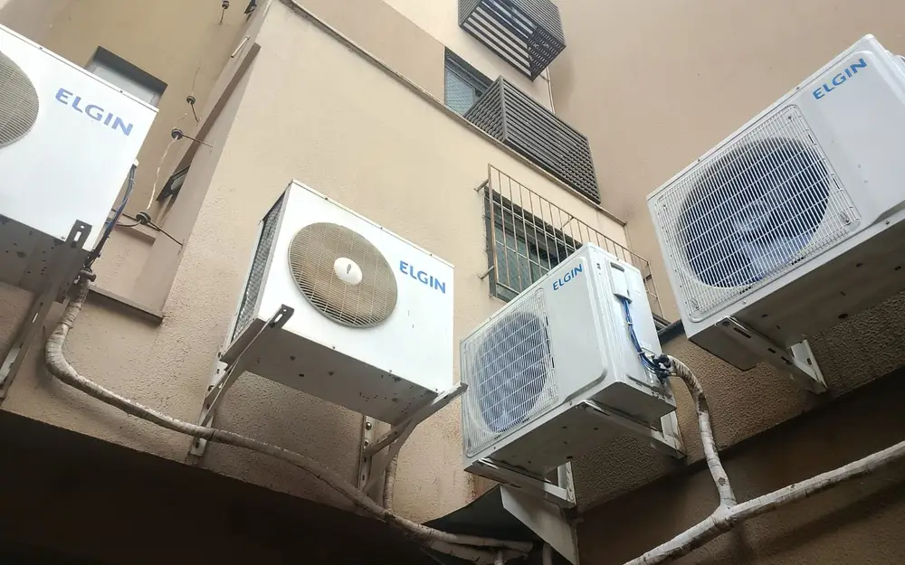 Serviços da SV Instalações: técnico em plataforma elevatória no teto de uma igreja e condensadoras de ar-condicionado instaladas em fachada