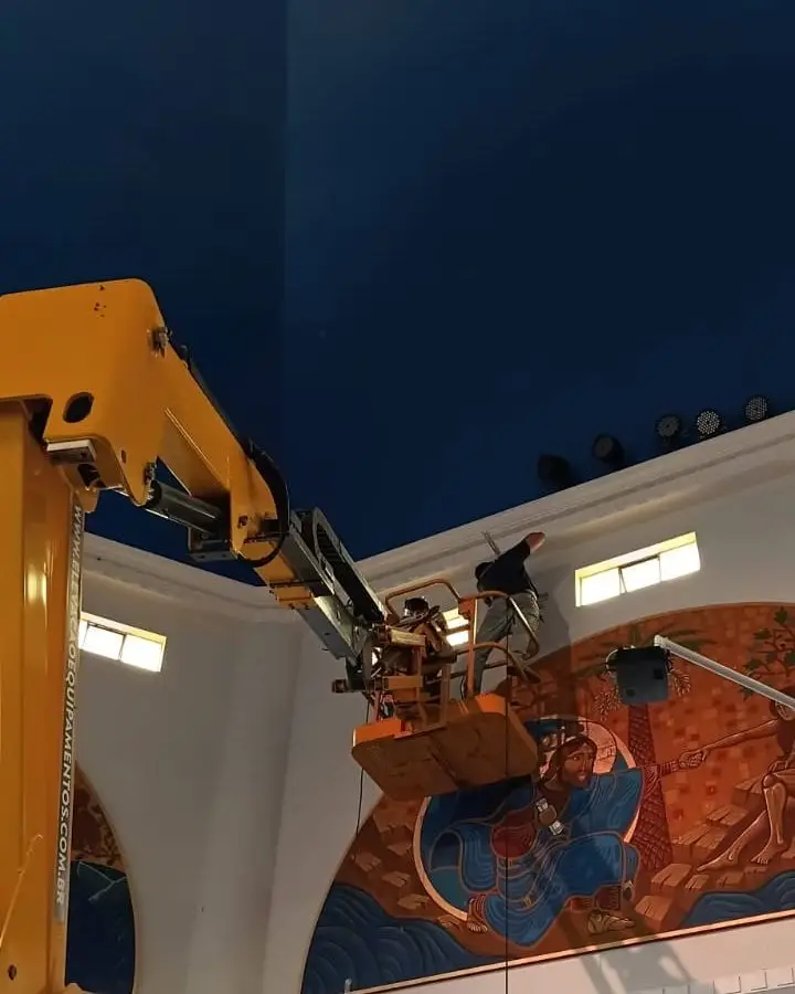 Técnico da SV Instalações trabalhando em plataforma elevatória no teto de uma igreja